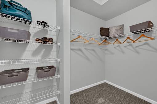 A walk in closet with clothes and shoes on shelves and hangers.