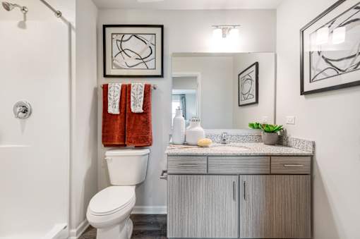 A bathroom with a toilet, sink, and two towels hanging on the wall.