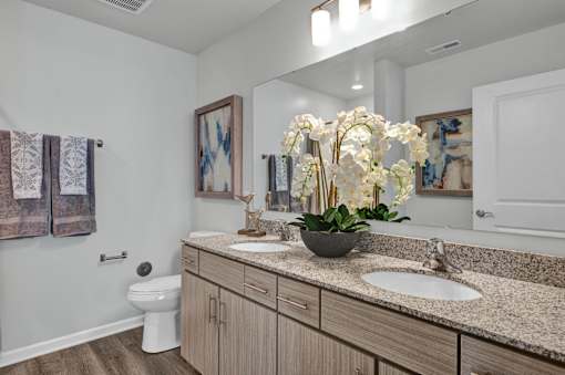 A bathroom with a toilet, sink, and a vase of flowers.