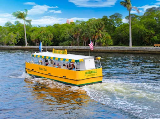 A yellow boat with the name "Lauderdale" written on it is sailing on the water.