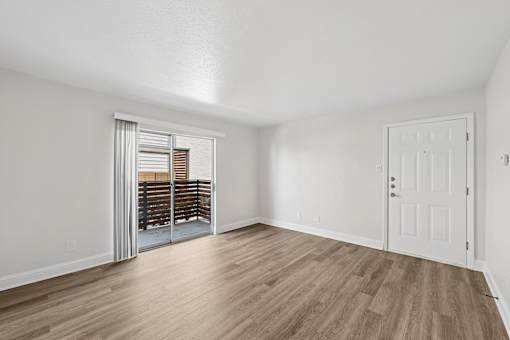 A room with a white door and a sliding glass door leading to a balcony.