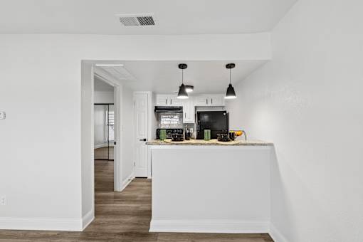 A kitchen with white walls and a wooden floor.