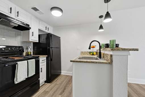 A kitchen with black appliances and a marble countertop.