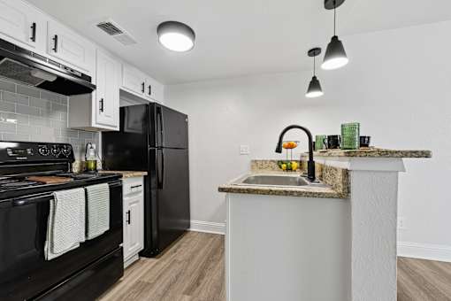 A kitchen with black appliances and a marble countertop.