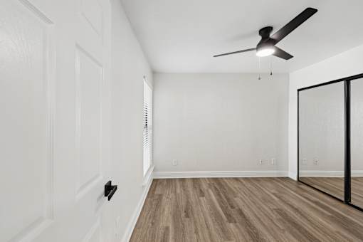 A room with a ceiling fan and wooden flooring.