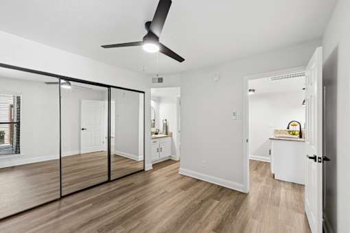 A room with a ceiling fan and a mirrored wall.