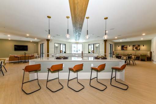 A modern kitchen with a long island and chairs.