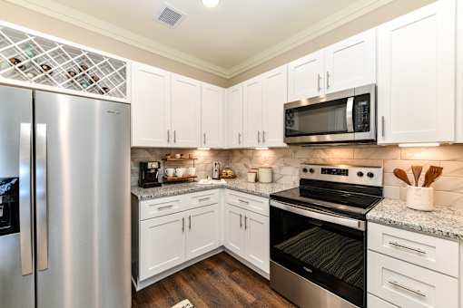 A kitchen with white cabinets and a stainless steel refrigerator.