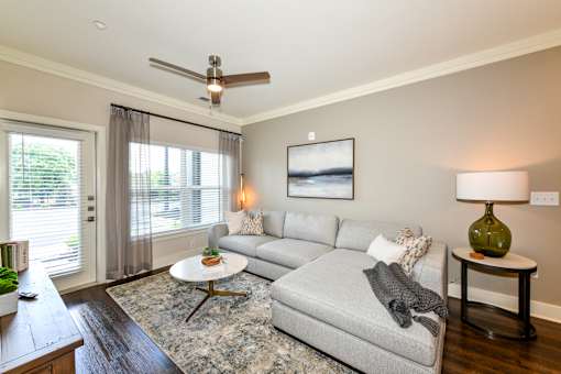 A living room with a grey couch, a green lamp, and a painting on the wall.