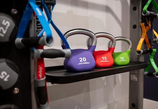 A set of colorful kettlebells are lined up on a rack, with weights ranging from 10 to 20 pounds.