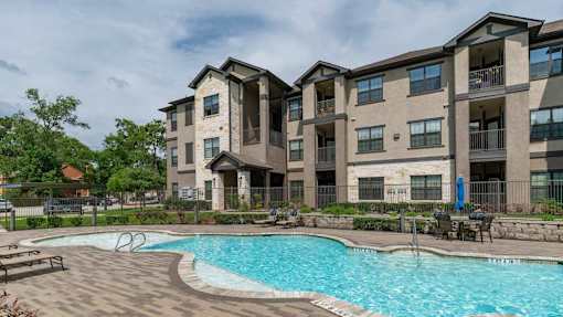 A large swimming pool is located in front of apartment buildings.