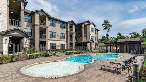A large apartment complex with a pool in the middle of the courtyard.