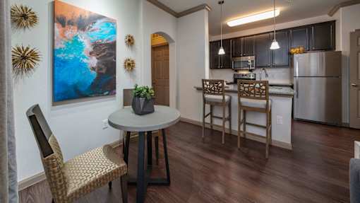 A kitchen with a table and chairs and a painting on the wall.