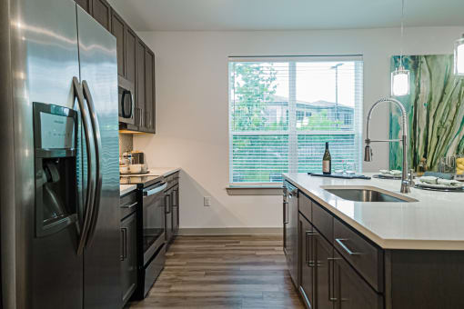 a kitchen with dark cabinets and a large window