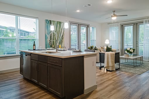 a kitchen with a large island and a living room in the background