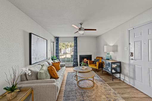A living room with a grey couch, a yellow chair, a coffee table, a fireplace, and a painting on the wall.