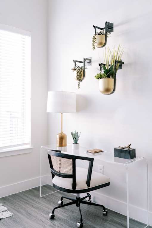 A white desk with a black chair and a white lamp.