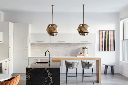 A kitchen with a black marble island and a dining table with four chairs.