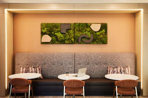 A modern cafe with a green leafy painting on the wall.