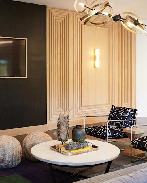 A modern living room with a round table and a chair with a black and white pattern.