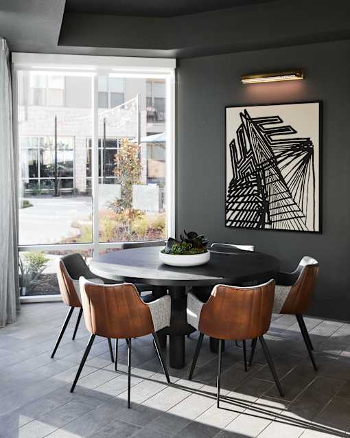 A dining table with chairs and a framed artwork on the wall.