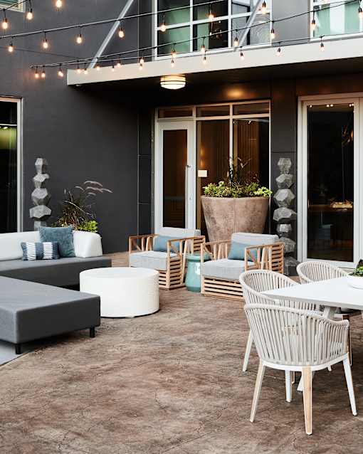 A patio with a table, chairs, and a potted plant.