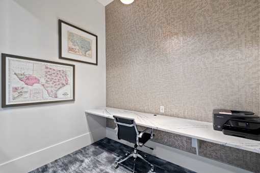 A room with a desk, chair, and two pictures on the wall.