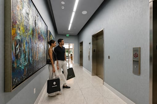 Two people walking down a hallway carrying shopping bags.