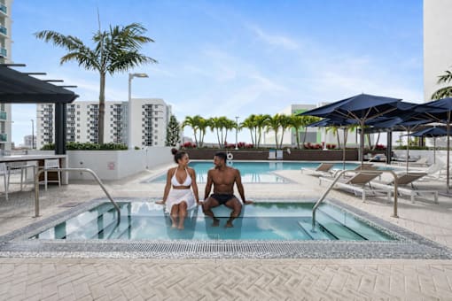 Two people are sitting in a pool on a sunny day.