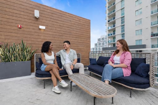 Three people are sitting on a bench and talking to each other.