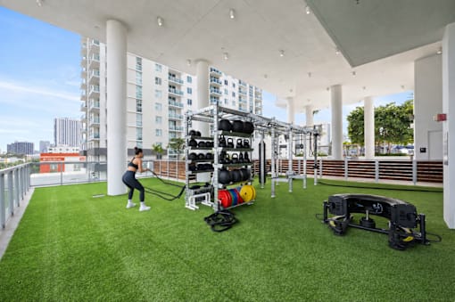 A woman is exercising in a gym with a green floor and white pillars.