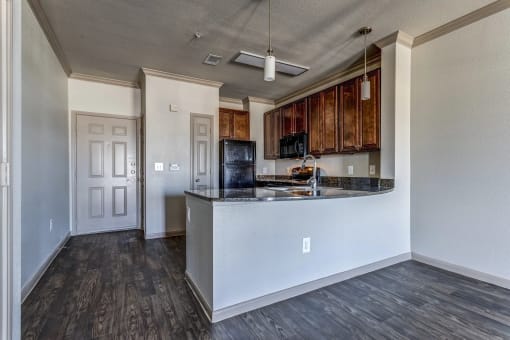 an empty living room with a kitchen in the background