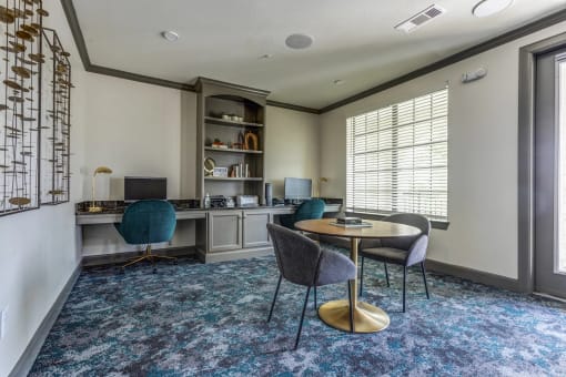 a room with a desk and chairs and a large window