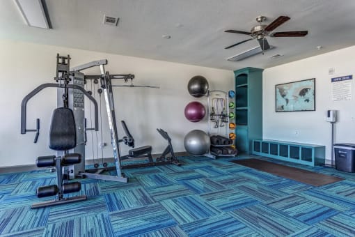 a home gym with exercise equipment and a ceiling fan