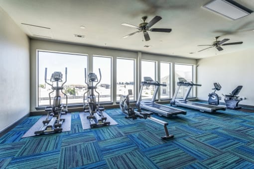 a gym with cardio equipment and large windows with a view of the water