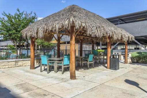 a patio with a thatched umbrella and tables and chairs