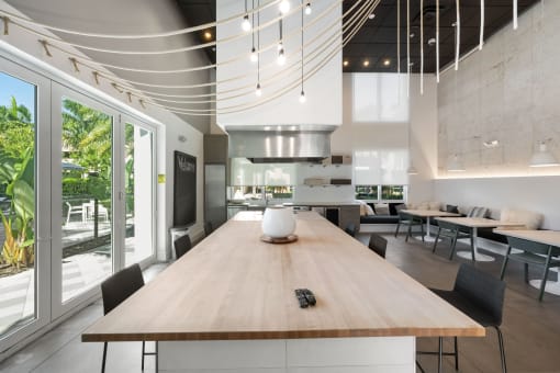 a large dining room with a wooden table and a kitchen in the background