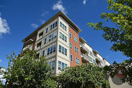A tall building with a red brick facade and balconies.