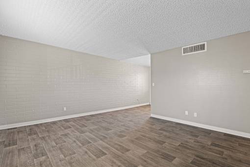 A room with wooden flooring and a wall-mounted air conditioner.