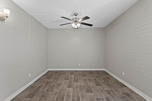 A room with a ceiling fan and wooden flooring.