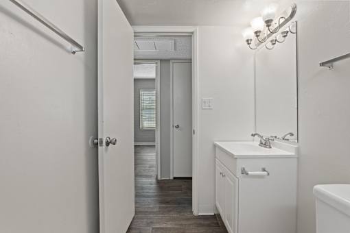 A white bathroom with a sink and mirror.