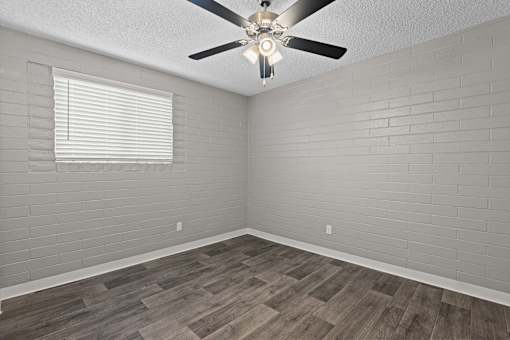 A room with a ceiling fan and wooden flooring.