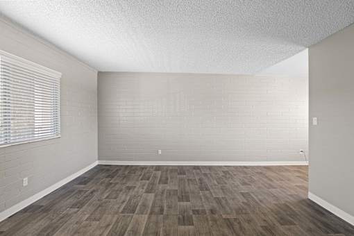 A room with wooden flooring and a window with blinds.