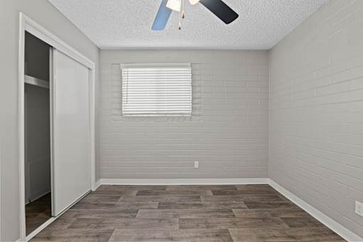 A room with a ceiling fan and a window with blinds.