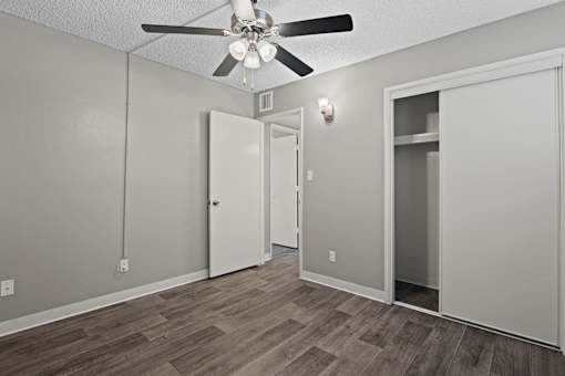 A room with a ceiling fan and wooden flooring.
