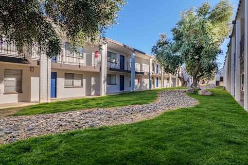 A row of apartment buildings with a grassy area in front.