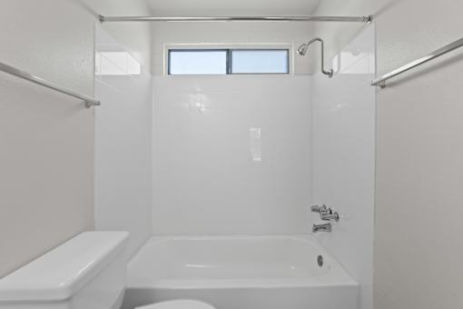 A white bathroom with a tub, toilet, and sink.