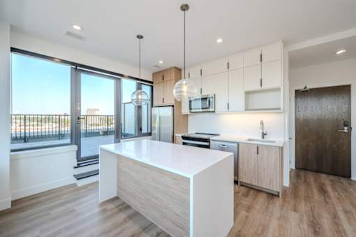 a white kitchen with a large island and a balcony