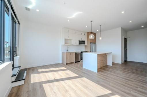an open kitchen and living room with wood floors and white walls