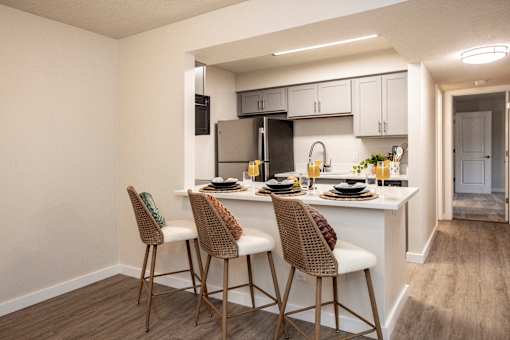 A kitchen with a white countertop and brown chairs.